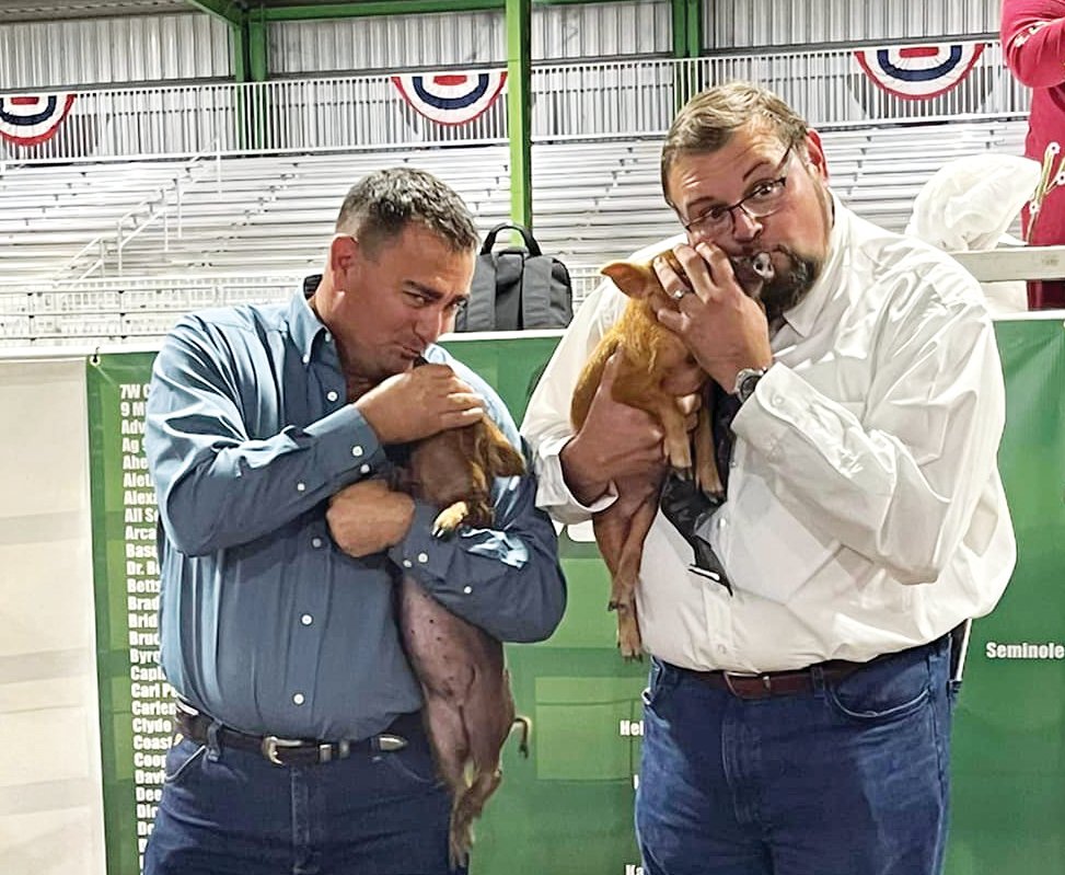 Tony Whidden and Marcos Montes De Oca kissed pigs as a fundraiser for Project Graduation. [Photo courtesy Project Graduation]